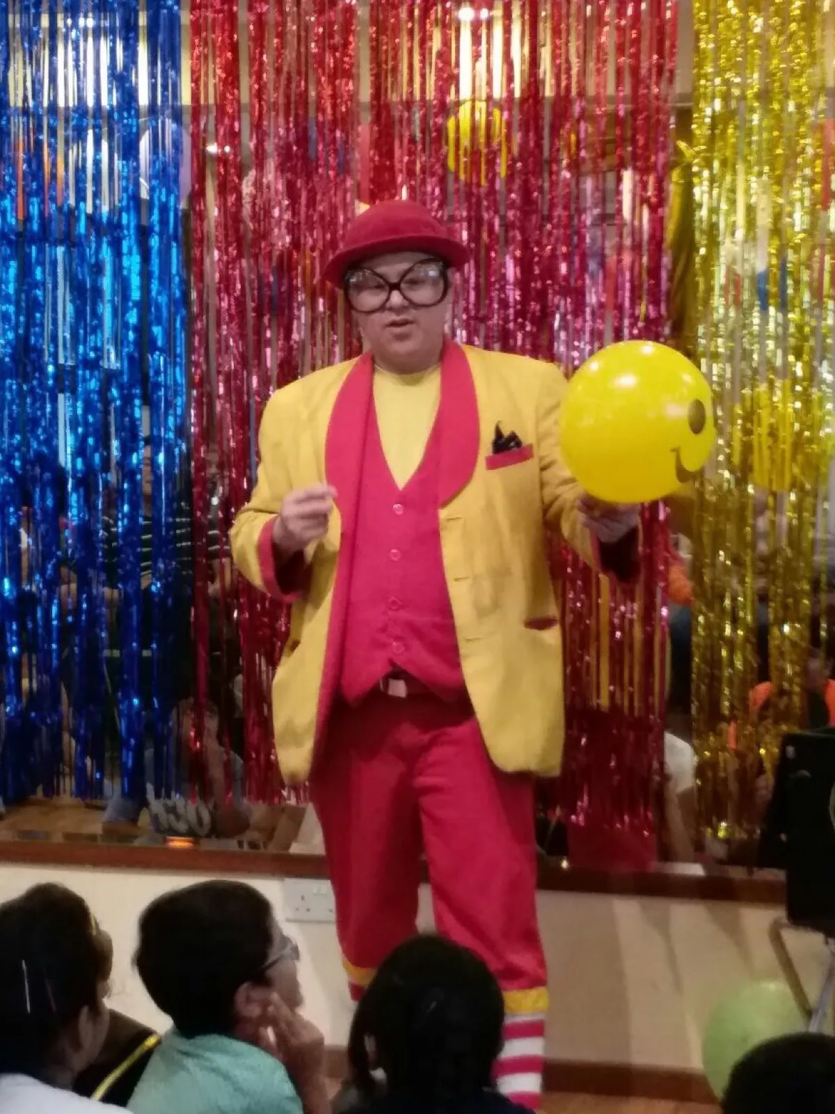 Maddie the 'Mad' Magician performing to a crowd of children with a giant smiley balloon